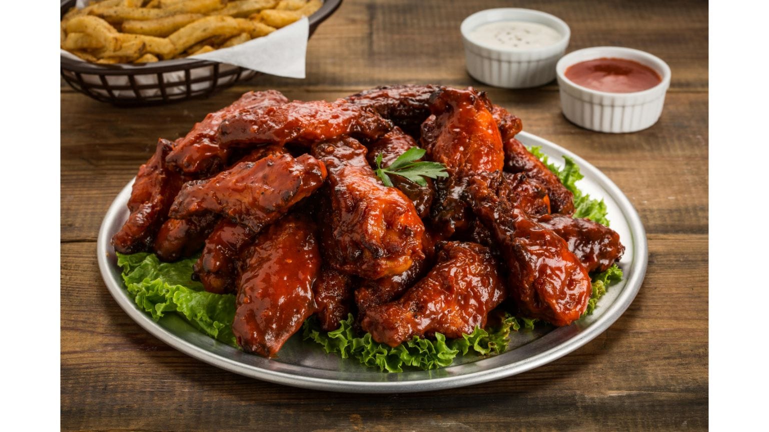 Plate of crispy buffalo chicken wings with celery sticks and dipping sauce on the side.